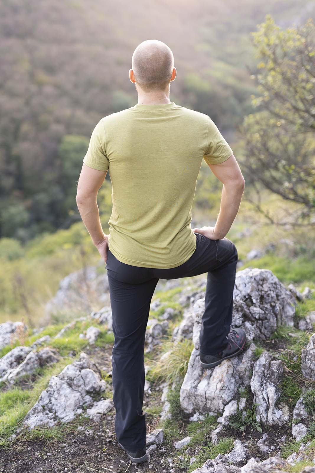 Muž počas západu slnka vystupuje na kopec. Je otočený chrbtom, má oblečené zelené tričko značky kallys, ktoré sa nazýva Supreme Silk a je z merina a tencelu