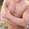 Detail na pánske merino tričko summit s dlhým r ukávom. Tričko je hnedej farby a detail je zamerany na prsia muža s logom kallys a preloženými rukami.